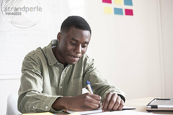 Schwarzer junger Mann  der auf einem Tisch studiert