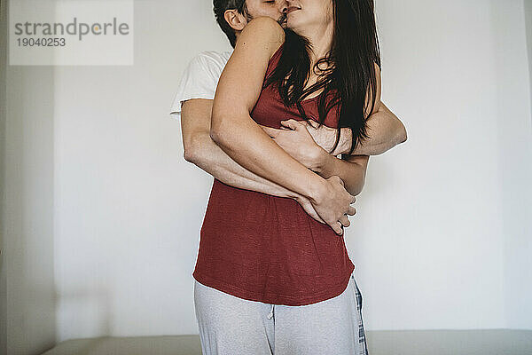 Junges glückliches Paar umarmte sich morgens im Pyjama