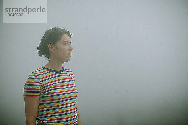 Junge Frau im Nebel blickt in die Ferne