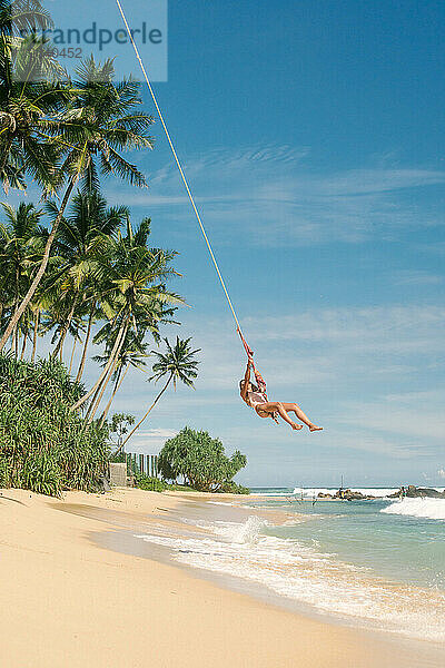 Mädchen schwingt auf einer Palme am Strand in Sri Lanka