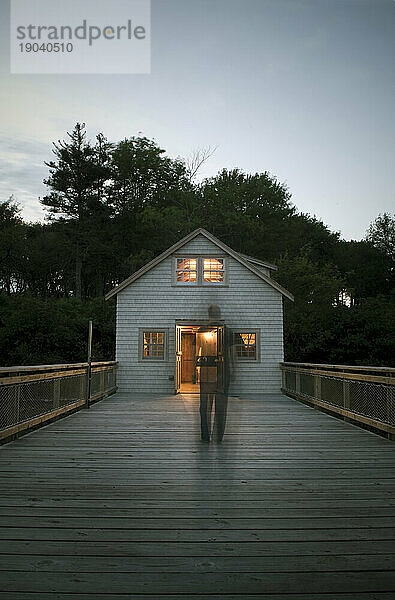 Mann geht in der Abenddämmerung an Deck in Richtung Hütte  Maine.