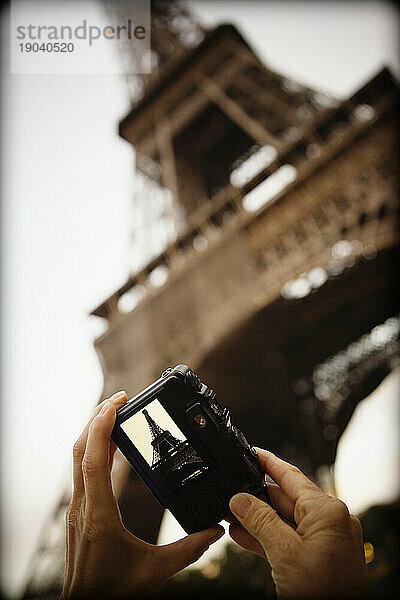 Eine Frau macht ein Foto vom Eiffelturm.