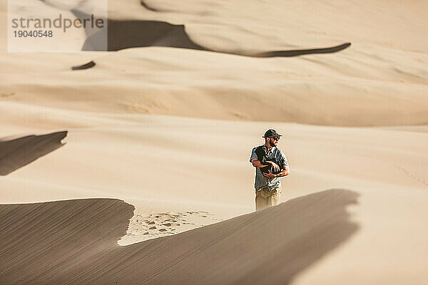 Dünenwanderer schützt seinen Welpen im großen Sanddünenpark vor dem Wind
