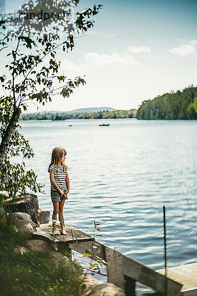 Schönes blondes Mädchen  das an einem sonnigen Tag den See betrachtet