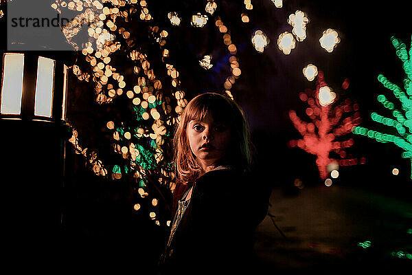 junges Mädchen in der Nacht mit Weihnachtsbeleuchtung und Bokeh und Straßenlaterne