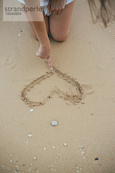 Junge Frau formt ein Herz im Sand