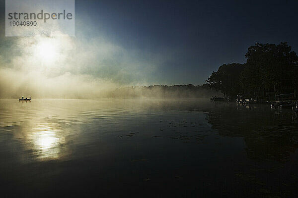 Silhouette zweier Fischer am Palmer Lake in Michigan mit frühem Morgennebel.