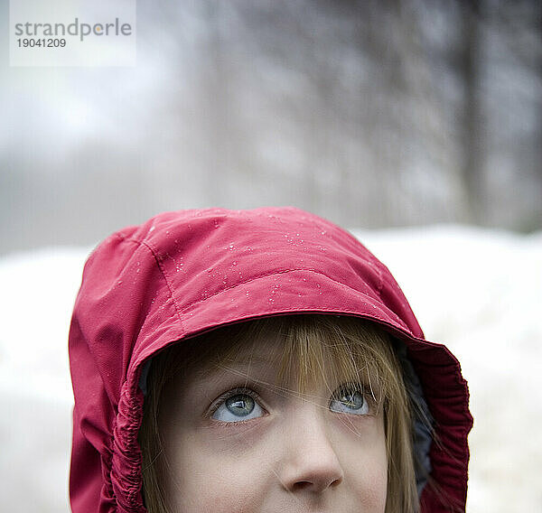 Kind schaut nach oben  Nahaufnahme  trägt einen Regenmantel im Freien  Maine.