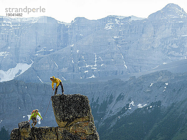 Bergsteigerpaar erklimmt Felsgipfel  Berge