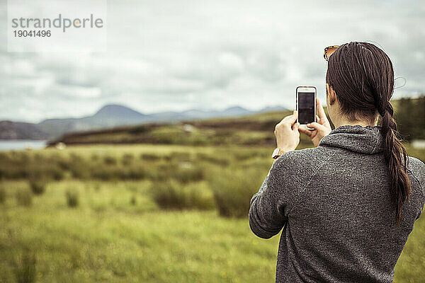 Junge Frau fotografiert die Berglandschaft der schottischen Highlands