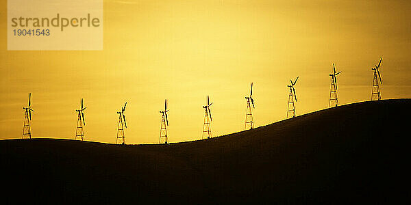 Panorama der Silhouetten von Windkraftanlagen auf einem Hügel bei Sonnenaufgang  Kalifornien.