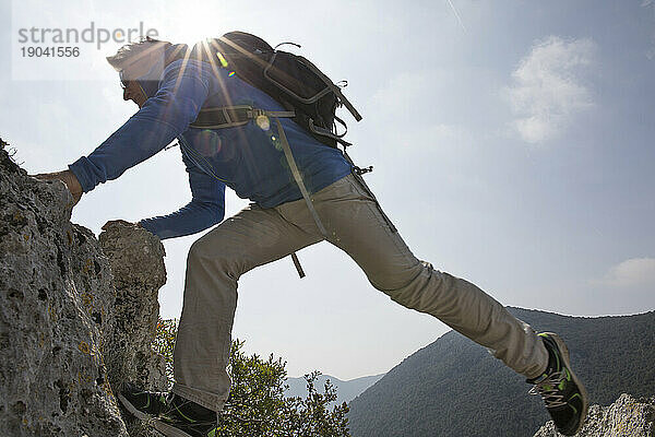 Wanderer streckt sich über Felsspalte in den Bergen