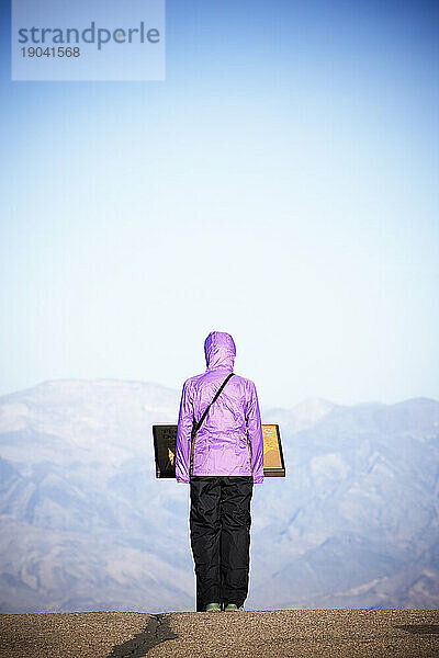 Rückansicht einer einsamen Frau  die an einem Hinweisschild am Dantes View steht. Death Valley Nationalpark  Kalifornien.
