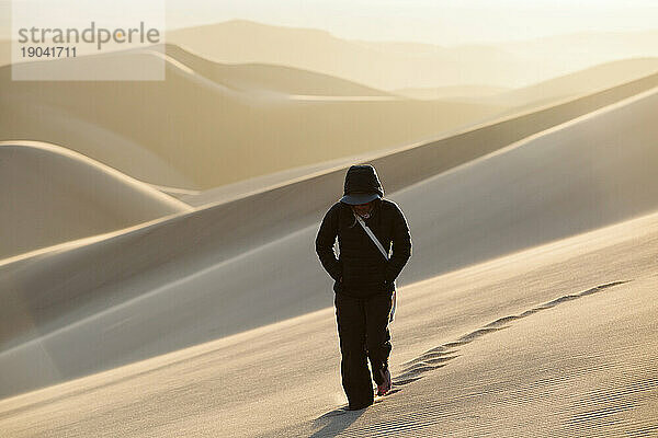 Wanderer mit Kapuze wandert durch die Wüste des Nationalparks Great Sand Dunes