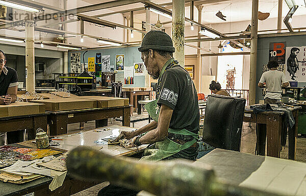 Ein kubanischer Künstler malt an seinem Tisch in einem Kunstatelier und einer Kooperative. Alt-Havanna oder Habana Vieja  La Habana  Kuba