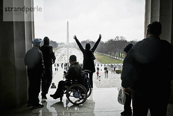 Eine Person posiert für ein Foto auf den obersten Stufen des Lincoln Memorial gegenüber dem Washington Monument.