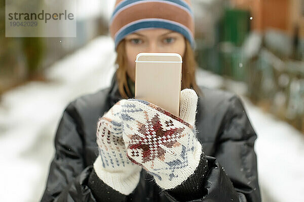 Frau in Winterhandschuhen hält Smartphone  Moskau  Russland