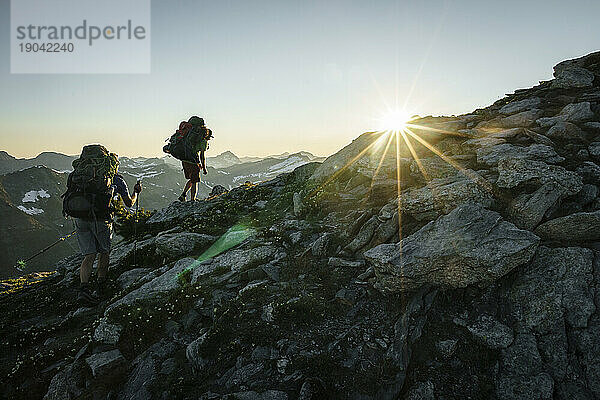 Silhouette zweier Wanderer bei Sonnenuntergang mit Bergen im Hintergrund  BC