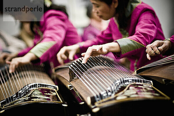 Eine Gruppe von Gu-Zheng-Spielern steuert mit ihren Fingern die Tonhöhe und das Vibrato jeder Note.