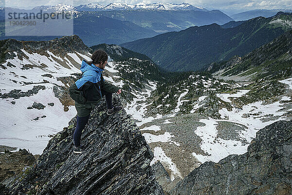 Junge Frauen auf einem Felsen blicken hinunter auf das Tal aus Bergen und Schnee  Kanada