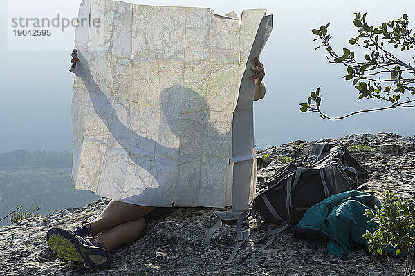 Detail einer Frau  die in der Karte auf einer Klippe über den Bergen silhouettiert ist