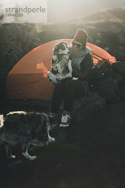 Camper und ihr Hund hängen im Camp bei Sonnenuntergang an den Kratern des Mondes herum