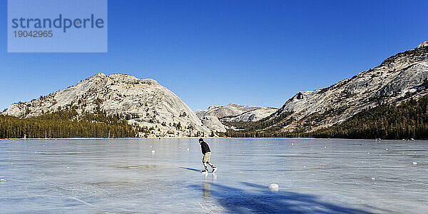 Ein einsamer Mann  der auf einem zugefrorenen See Schlittschuh läuft.