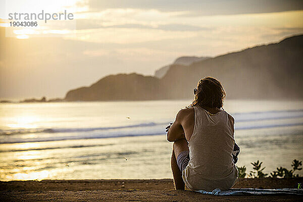 Junger Mann entspannt sich bei Sonnenuntergang  Lombok  Indonesien.