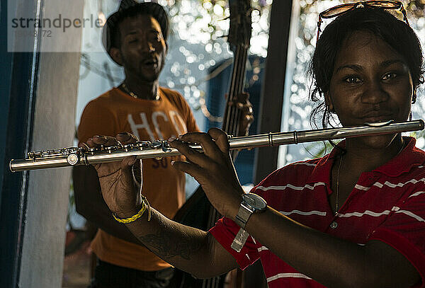 Lächelnde junge kubanische Musikerin  die mit einer Salsa-Band Flöte spielt. Trinidad  Kuba