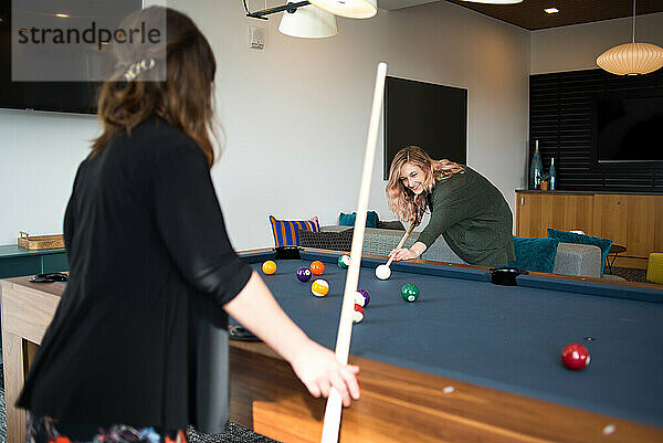 Zwei Frauen spielen gemeinsam Billard in der Wohnung