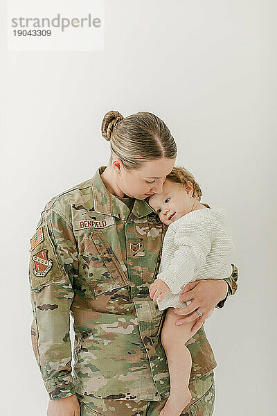 Baby kuschelt mit einer aktiven Militärmutter in Uniform