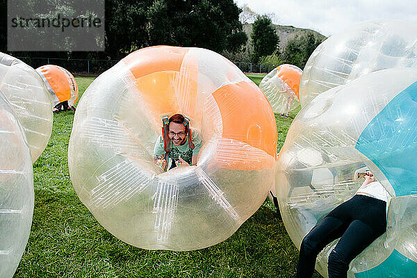 Mann lächelt  nachdem er beim Bubble-Soccer-Spielen niedergeschlagen wurde