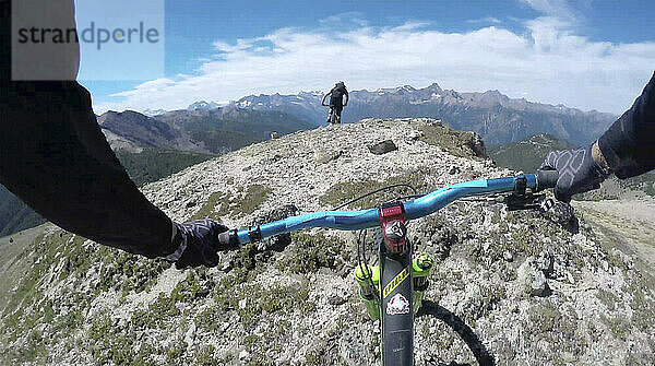 POV vorbei an den Händen eines Mountainbikers auf dem Bergkamm