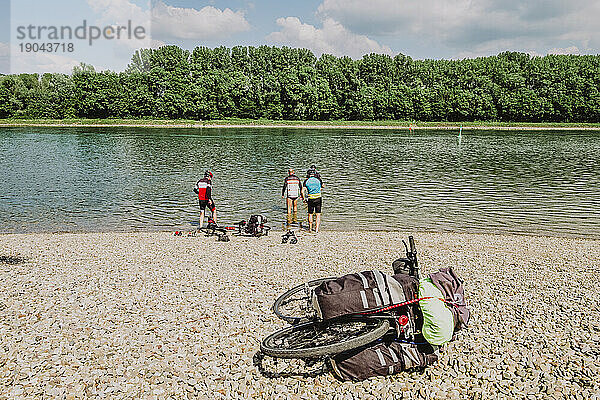 Eine Gruppe befreundeter Radfahrer im Wasser des Flusses Rin in Deutschland