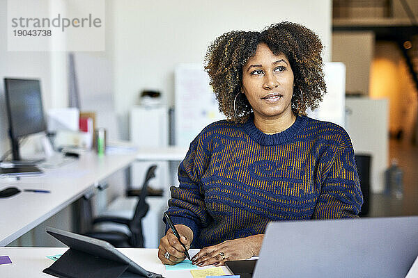 Nachdenkliche Geschäftsfrau mit Klebezetteln auf dem Schreibtisch im Büro
