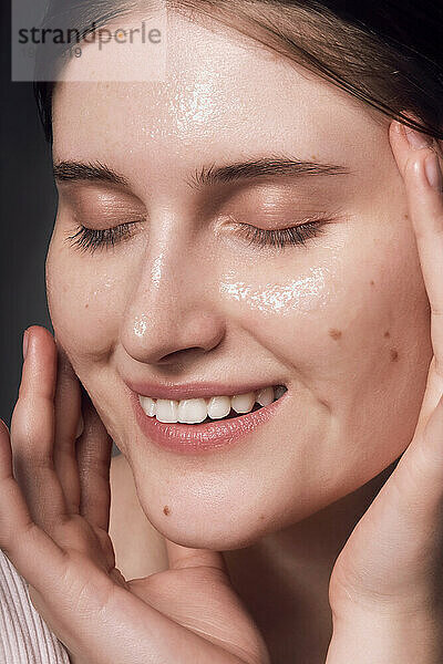 Face skin care. Woman applying a mask on clean hydrated skin portrait.