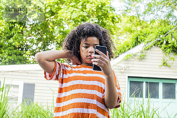 Tween posing on phone in backyard