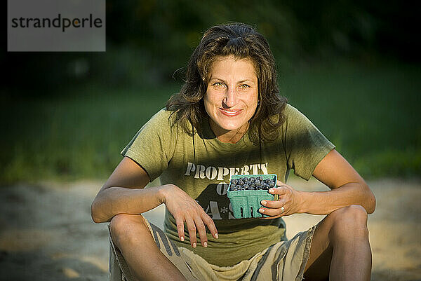 Frau entspannt sich am Strand und isst Blaubeeren.