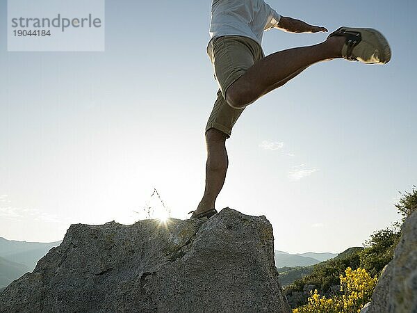 Mann springt auf Felsen über dem Meer