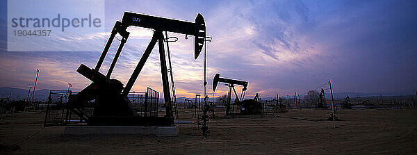 Silhouette von Ölbohrtürmen bei Sonnenuntergang im Midway-Sunset-Ölfeld im Kern County  San Joaquin Valley  Kalifornien in den Vereinigten Staaten