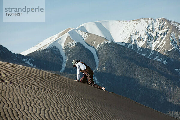 Müder Wanderer klettert auf Händen und Knien die Sanddüne hinauf
