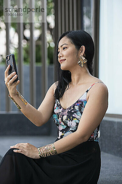 Schöne Thailänderin hält ihr Smartphone während eines Videochats