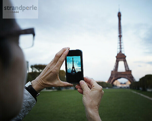 Eine Frau macht ein Foto vom Eiffelturm.