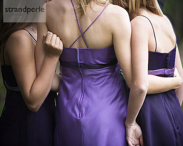 Rückansicht von drei Mädchen im Teenageralter in lila Kleidern.