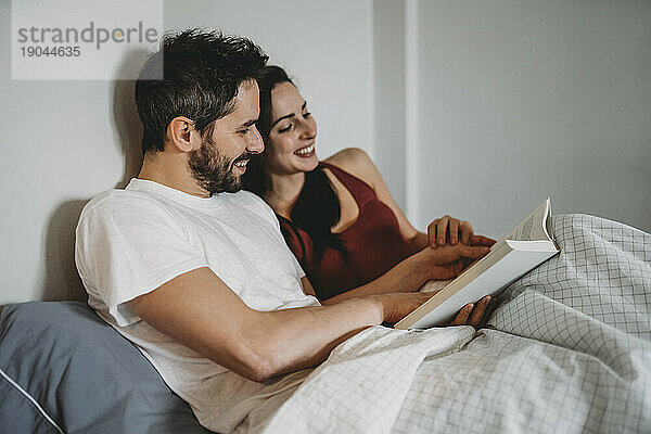 Liebespaar liest zu Hause unter der Bettdecke in einem Moment der Ruhe