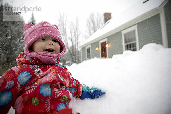 Junges Mädchen spielt im Schnee.
