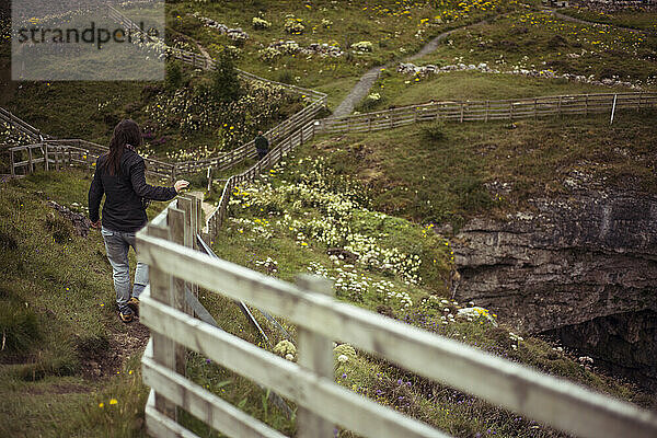 Mädchen läuft schroffen Zaun entlang zur Klippe