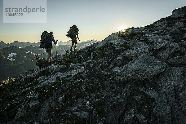 Silhouette zweier Wanderer bei Sonnenuntergang mit Bergen im Hintergrund  BC