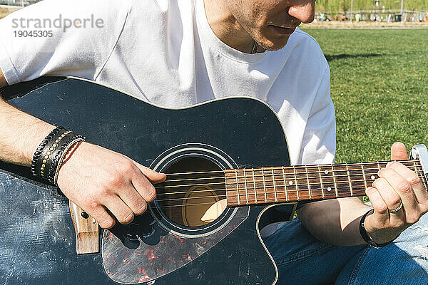 Nahaufnahme eines Sängers  der an einem sonnigen Tag in einem Garten Gitarre spielt