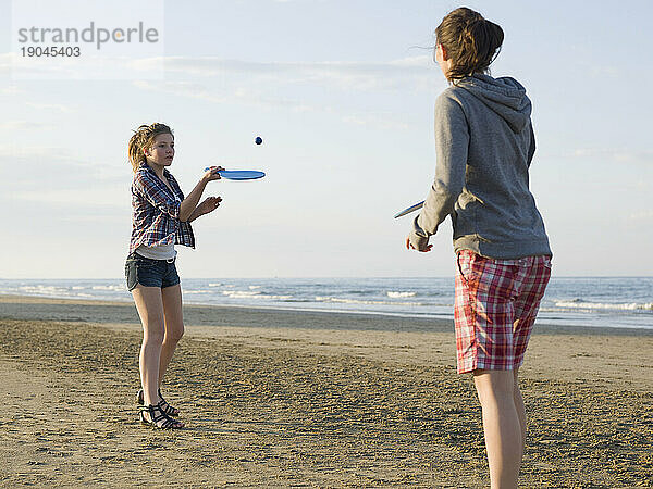 Teenager-Mädchen spielen Paddelball am Strand
